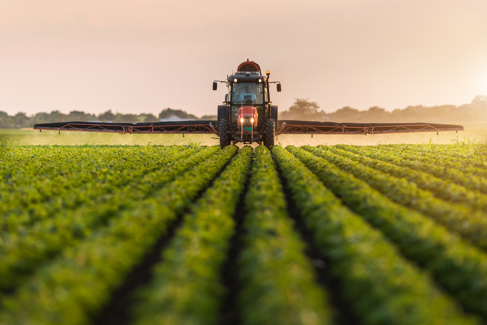 An autonomous tractor equipped with advanced agricultural technology operates in a vast, neatly organized field at sunrise, symbolizing the future of precision farming and innovative farming solutions.