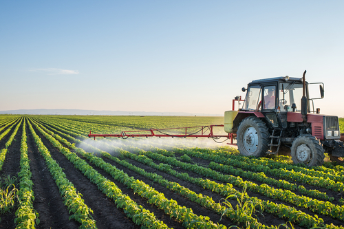 A tractor equipped with an auto steering system spraying crops in perfectly aligned rows, highlighting data-driven performance for optimal field management.