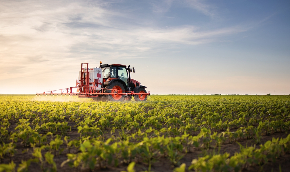 A tractor equipped with CHCNav GNSS technology working in a green agricultural field under a clear sky, showcasing advanced precision farming capabilities.