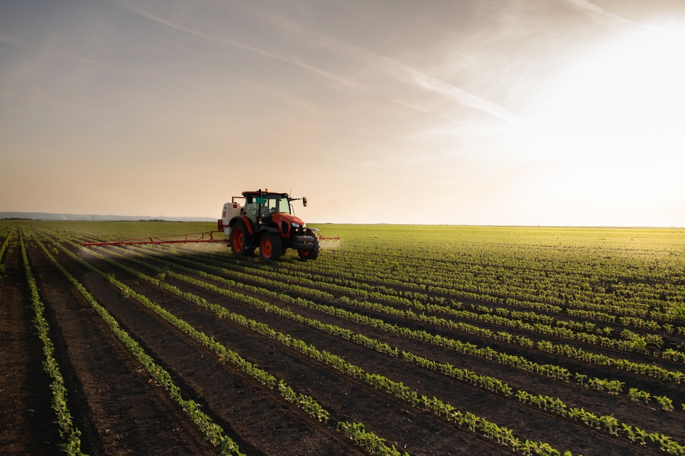 A tractor equipped with CHCNav GPS systems working in a large, well-organized agricultural field during sunset, demonstrating precision farming technology.